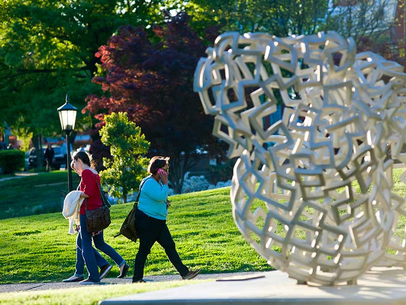 students walking past a sculpture on the v. c. u. campus